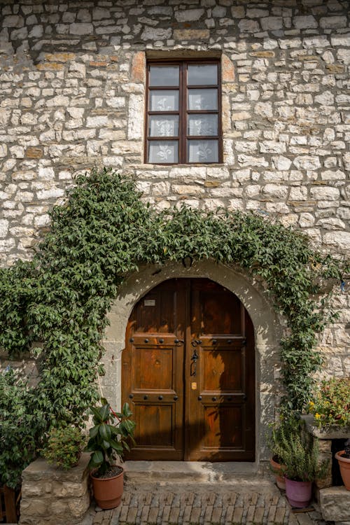 A stone house with a wooden door and potted plants