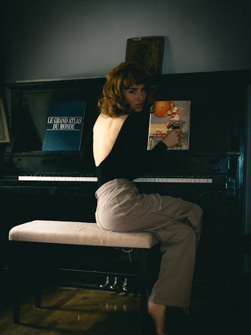 A woman sitting at a piano with a book