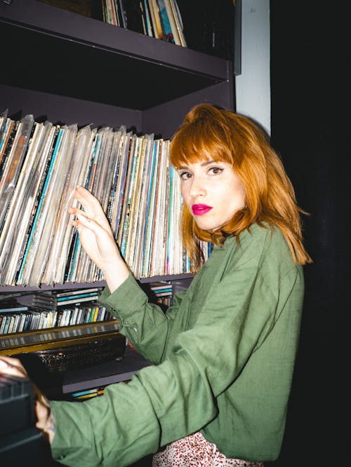 A woman with red hair holding a record player