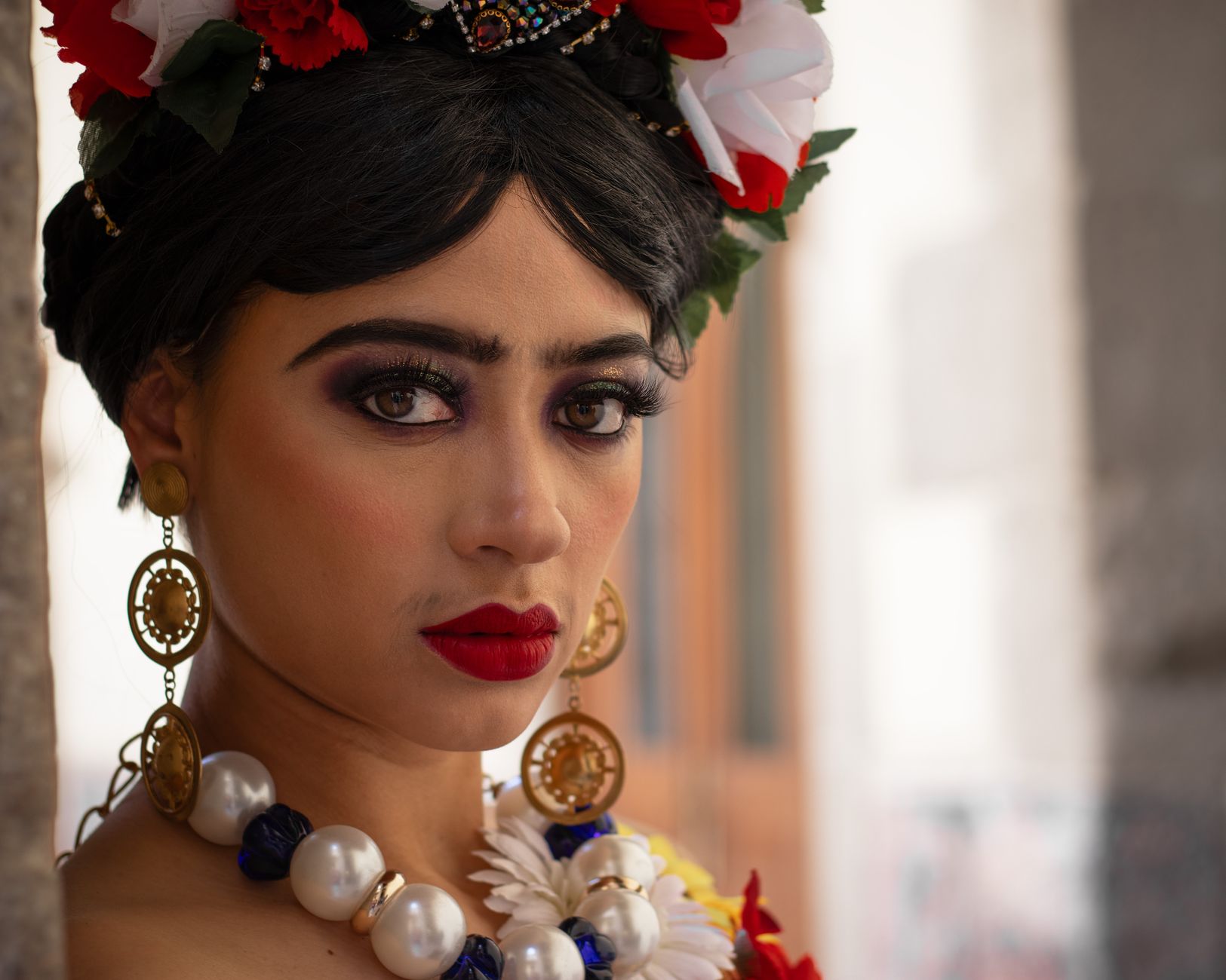 Striking portrait of a woman in floral headpiece with bold makeup, inspired by Frida Kahlo.