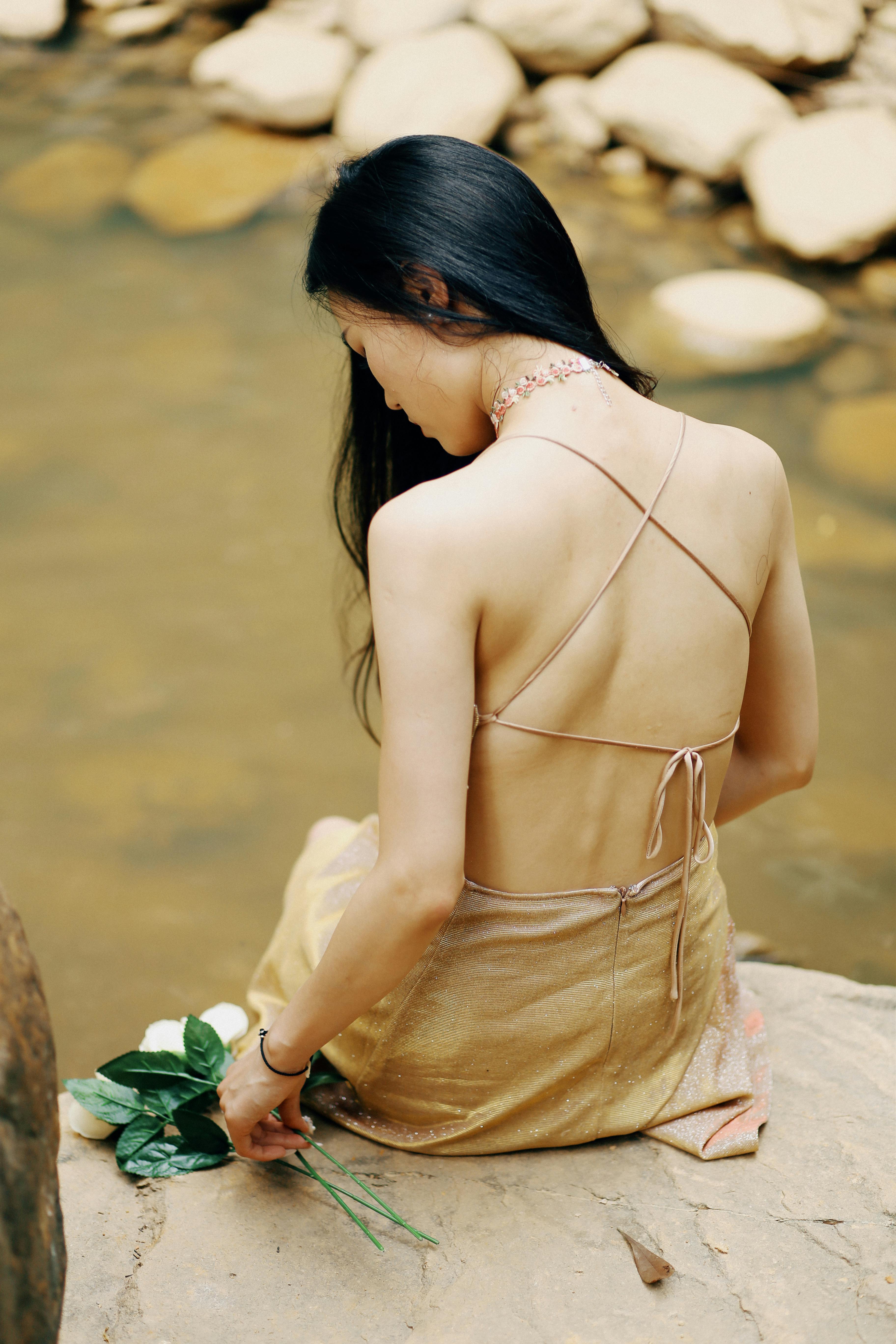 woman wearing golden dress sitting by the stream