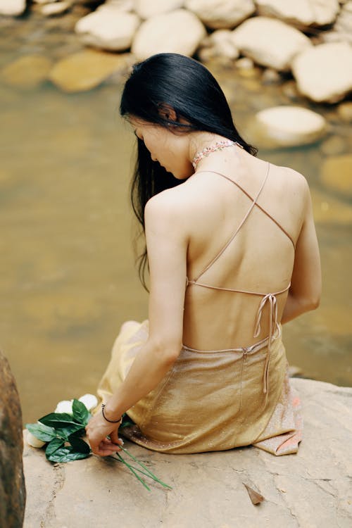 Woman Wearing Golden Dress Sitting by the Stream