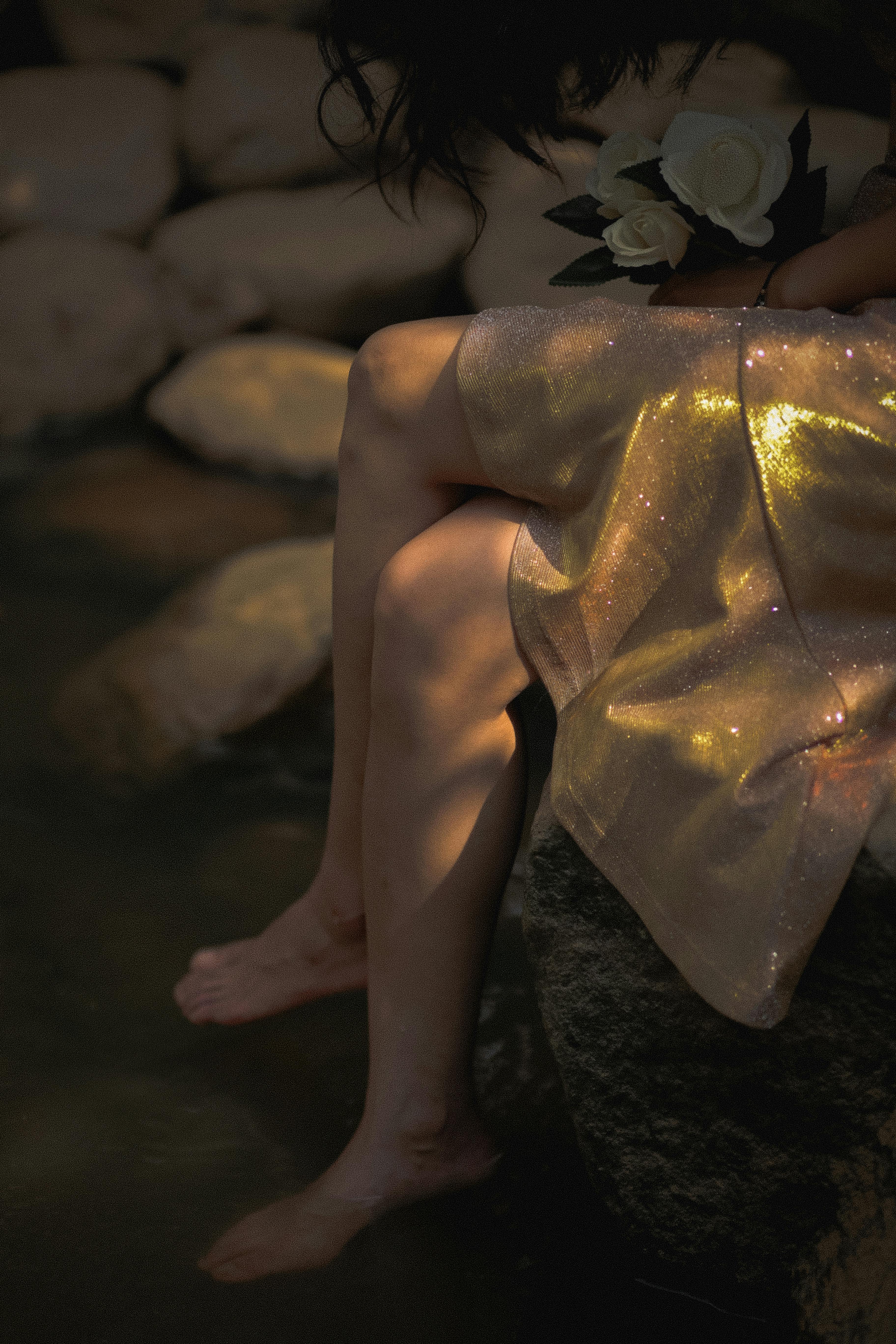 woman wearing golden dress sitting among rocks