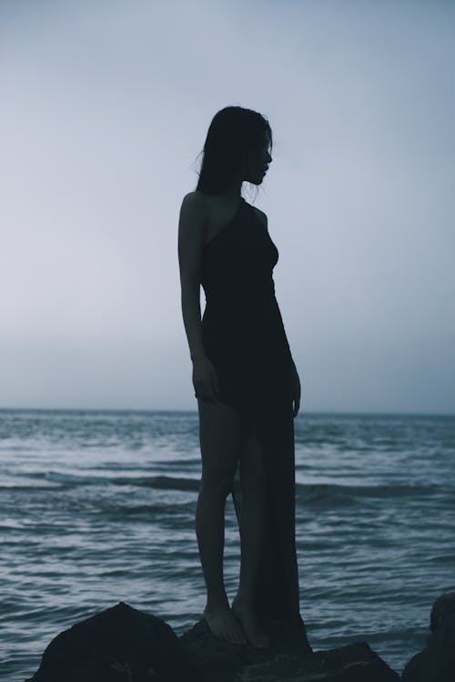 A woman standing on rocks by the ocean
