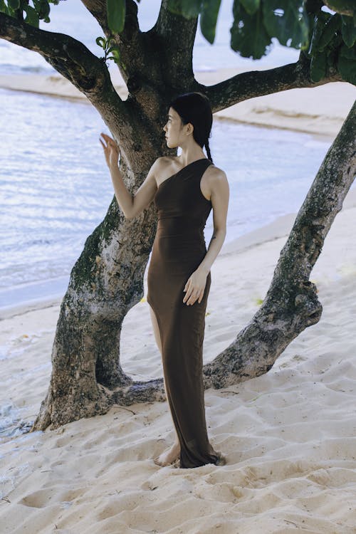 A woman in a brown dress standing near a tree