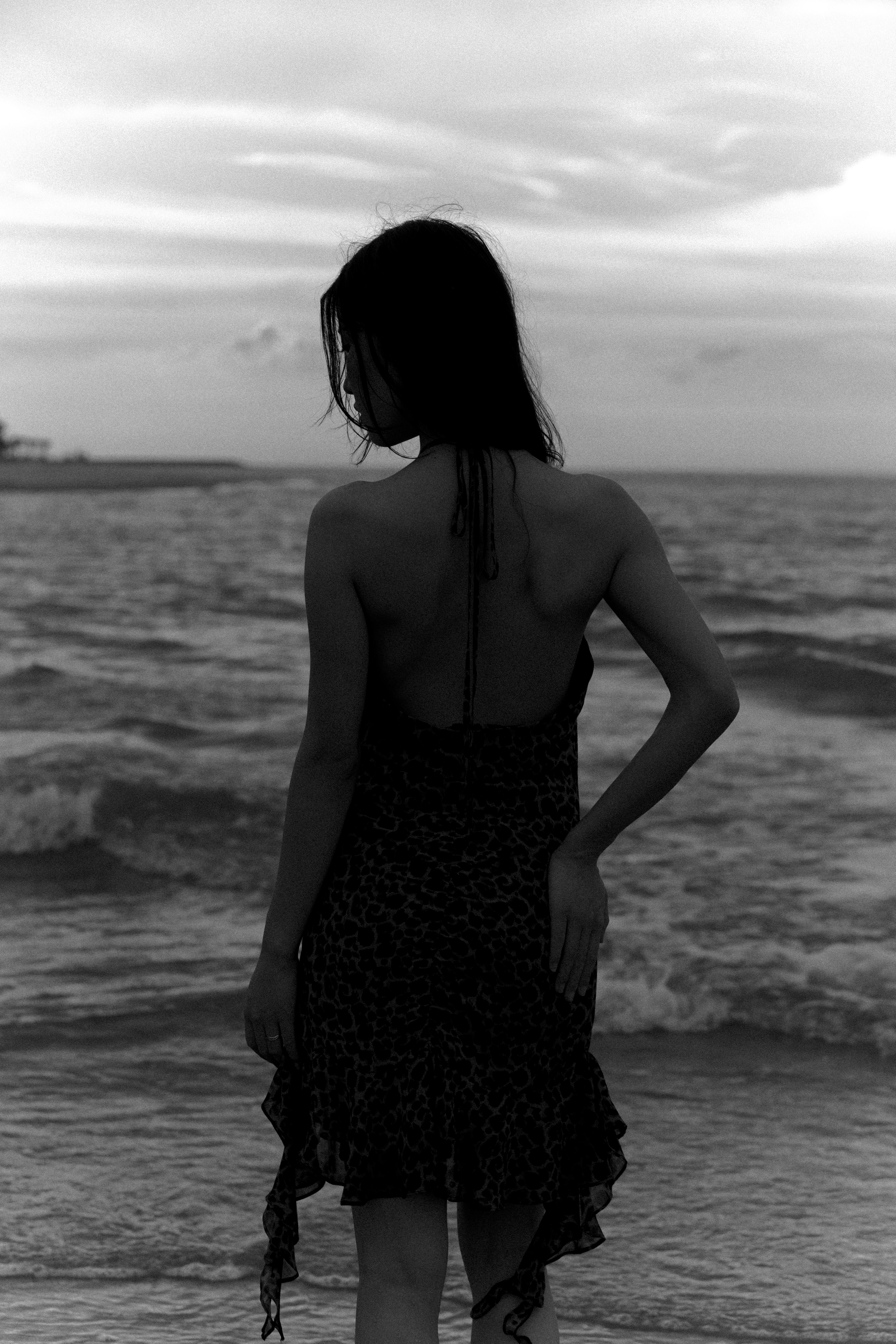 Monochrome silhouette of a woman at the seashore, conveying elegance and solitude.
