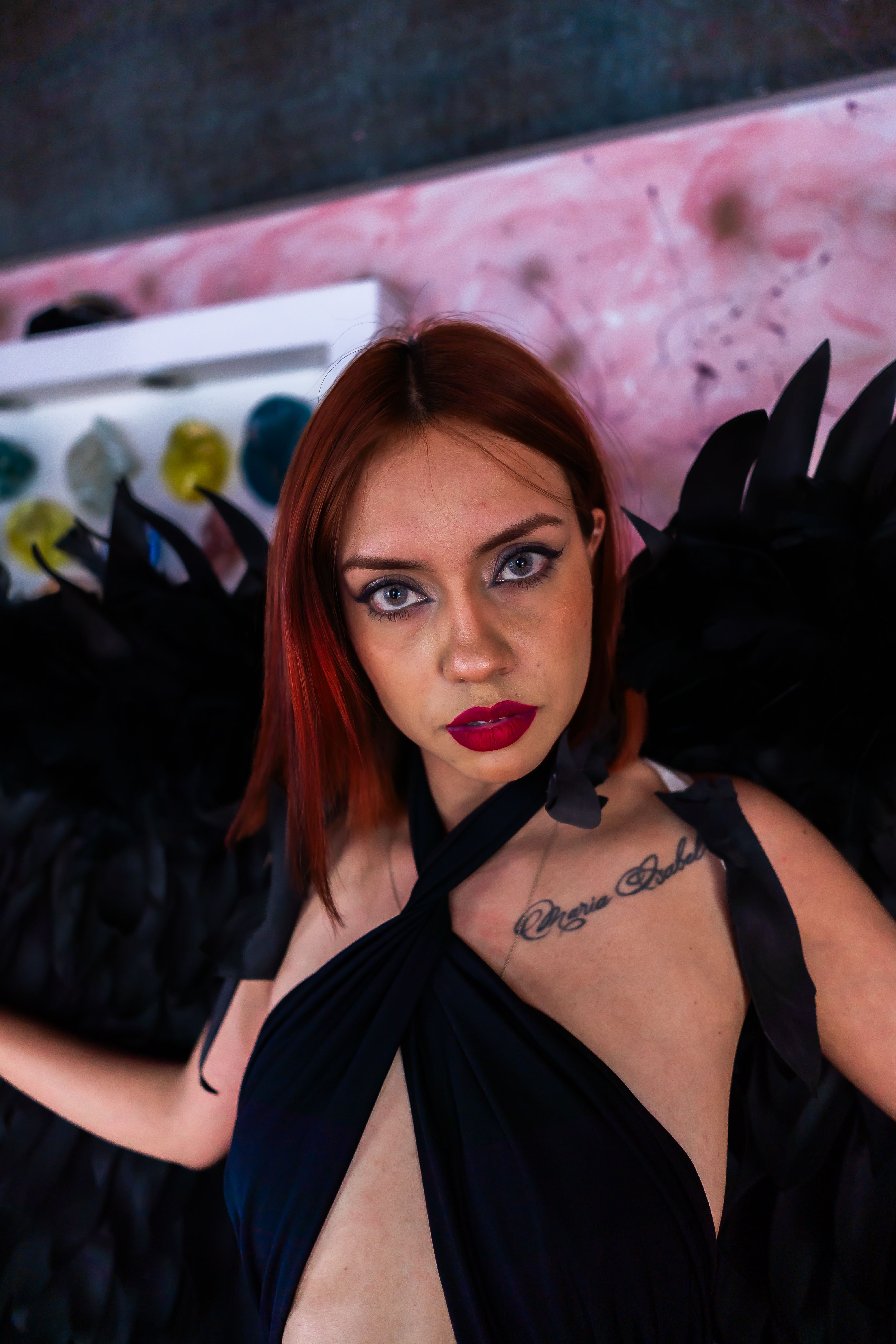 A striking portrait of a woman with black angel wings and vivid red hair in Mexico City.