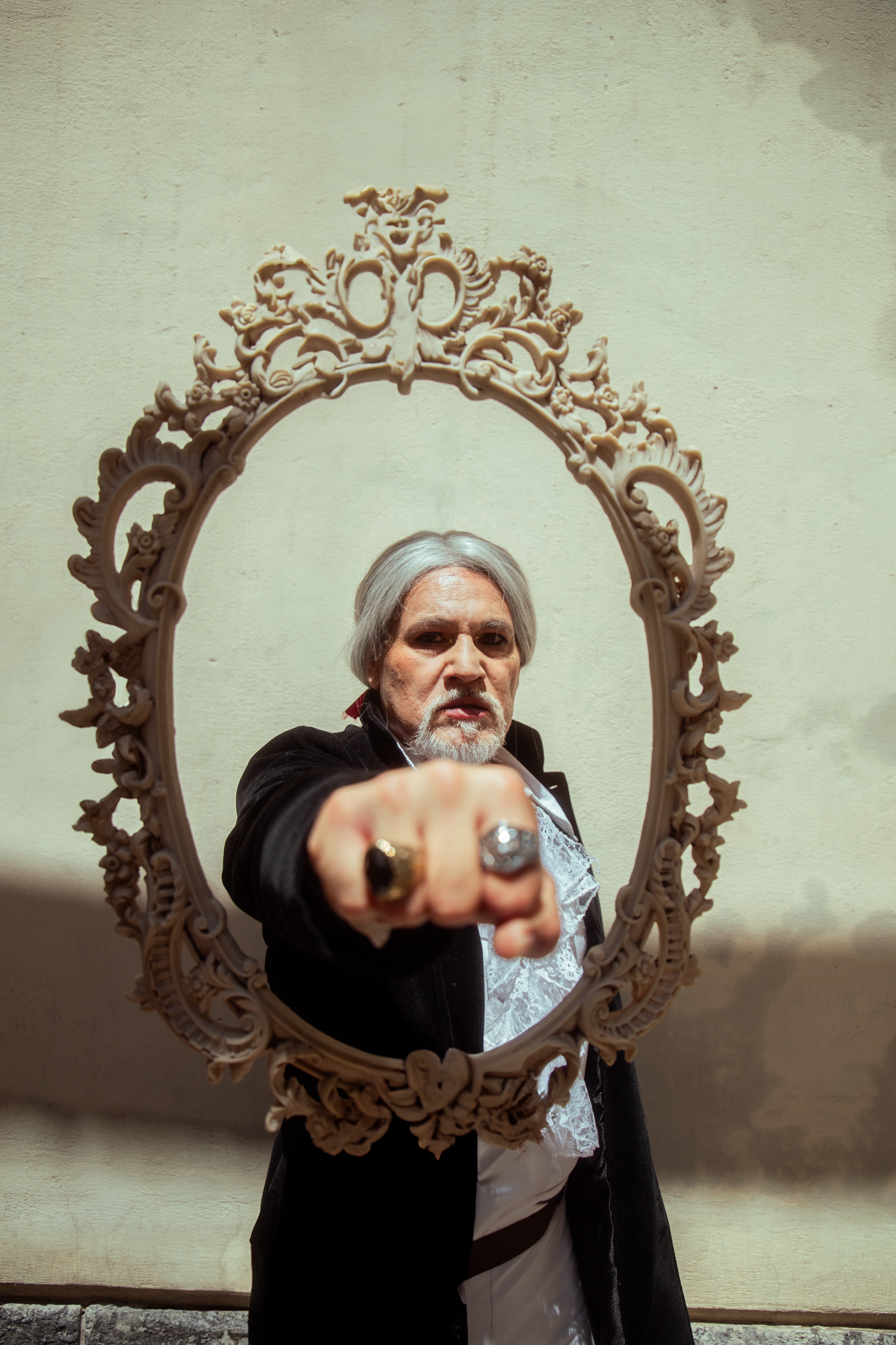 A man posing in an ornate frame, evoking a baroque aesthetic in daylight.