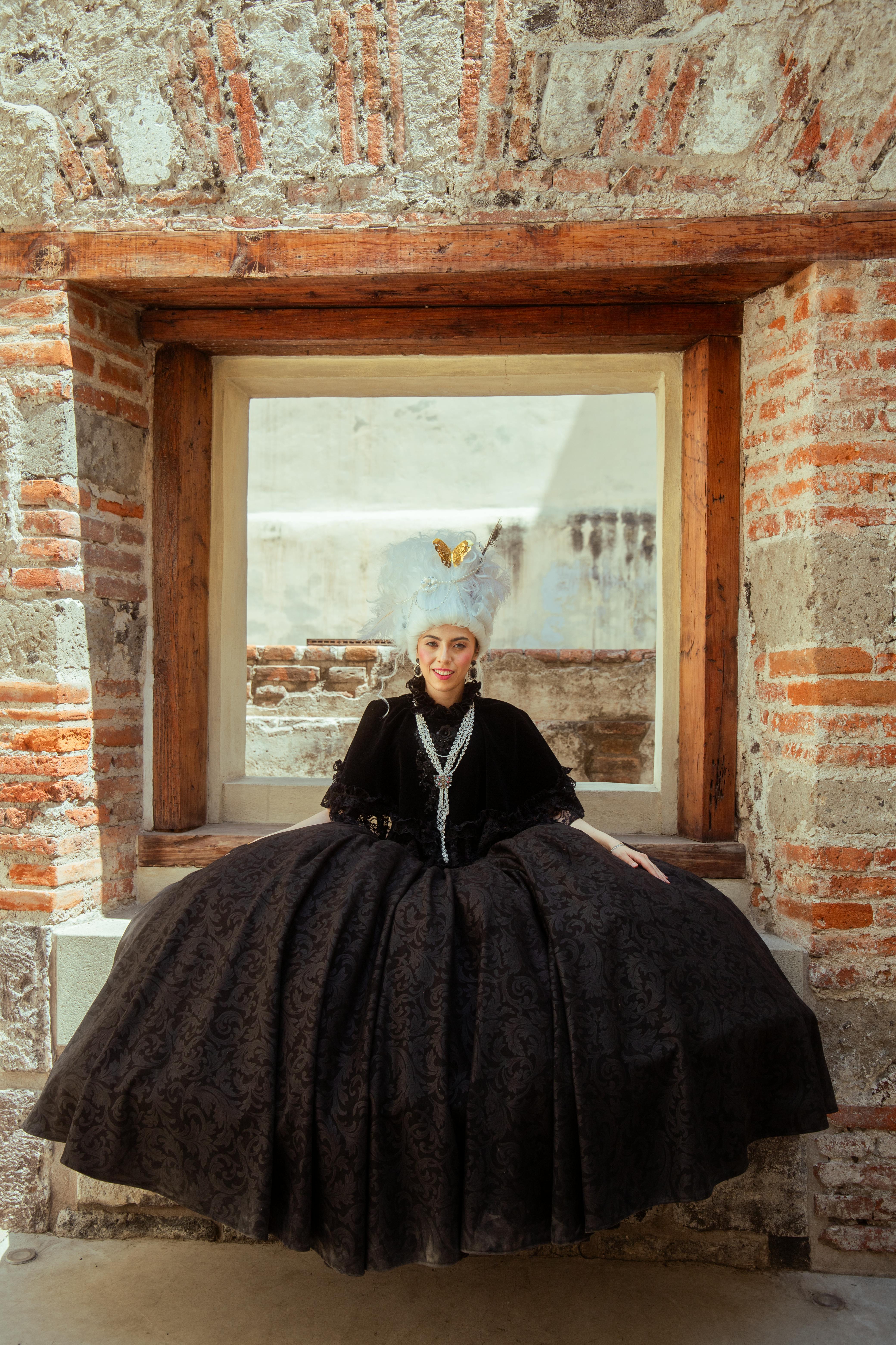 A woman in a vintage dress sits elegantly in an ancient architectural setting in Mexico City.
