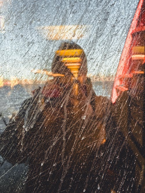 A man is reflected in a window on a train