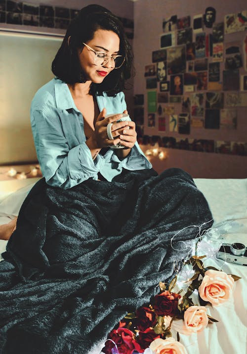 Женщина, сидящая на кровати с чашкой