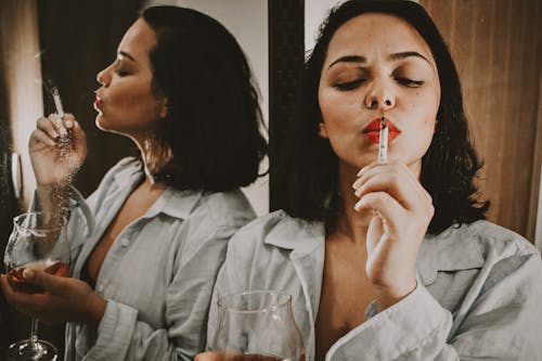 Woman Wearing Gray Collared Top Holding Cigarette Beside Mirror