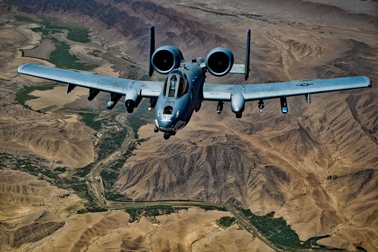 Gray Jet Fighter Flying Above Brown Mountain