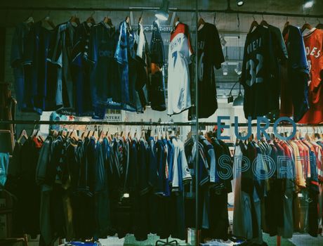 A variety of football jerseys on display in a Tokyo clothing store, highlighting a vibrant shopping scene.