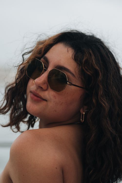 Free Portrait of a confident woman wearing sunglasses in natural light. Stock Photo
