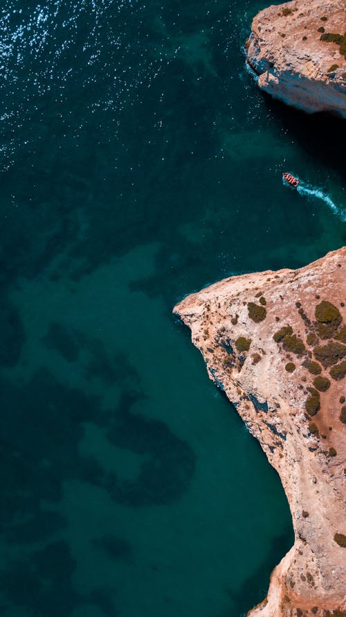 Aerial view of a cliff with a boat in the water