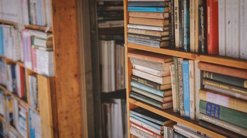 Free A warm and inviting wooden bookshelf filled with various books in a library setting. Stock Photo