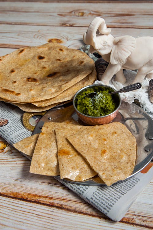 A plate of tortillas with a bowl of green sauce
