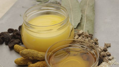Natural ingredients including bay leaves and oils arranged on a white background for culinary use.