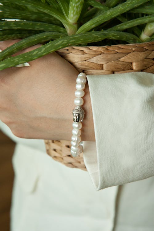 A woman holding a plant in her hand with a pearl bracelet
