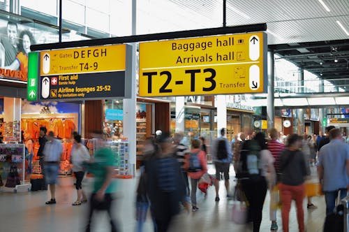 People Walking Beside Baggage Hall and Arrivals Hall Signage