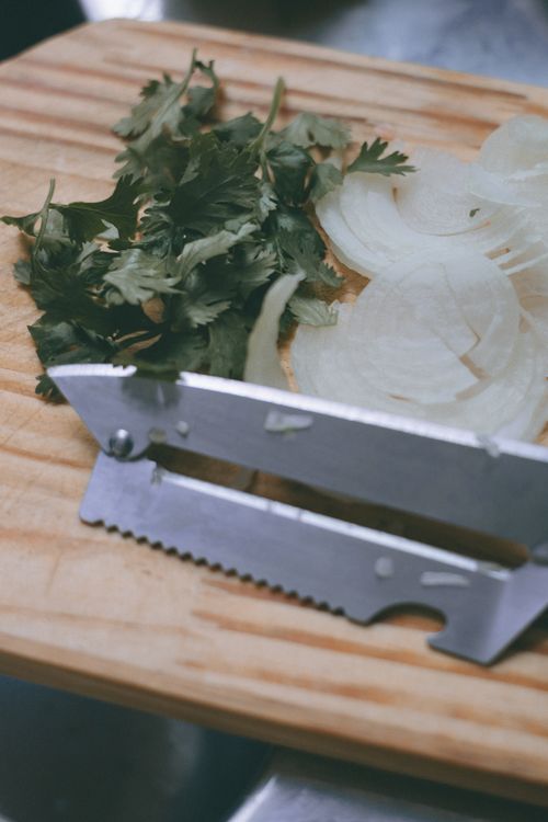 Free Close-up of sliced onions and fresh parsley on a wooden cutting board with a kitchen tool. Stock Photo