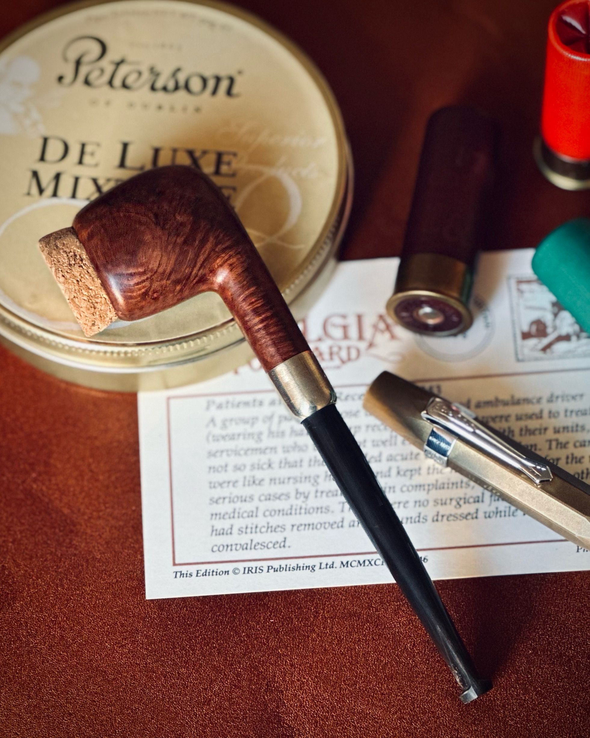 A classic wooden pipe and deluxe tobacco tin on a wooden surface, evoking a vintage feel.