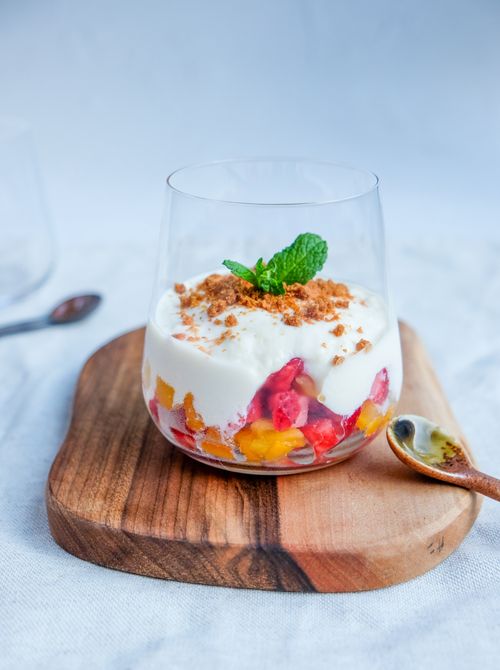 Free Close-up of a fruit and yogurt parfait with mint garnish on a wooden board, perfect for dessert lovers. Stock Photo