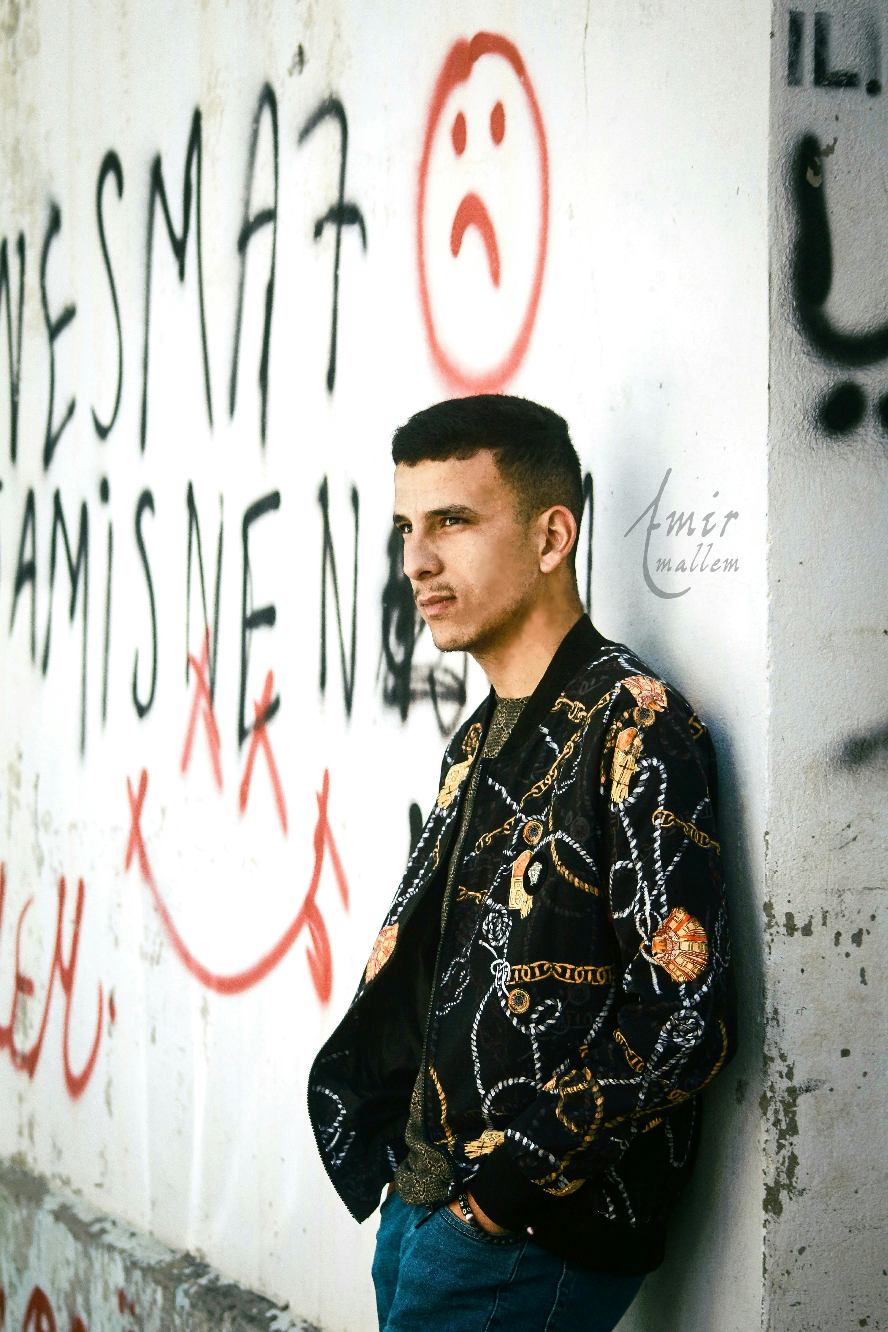 Portrait of a young man standing by graffiti-covered wall in Collo, Algeria.
