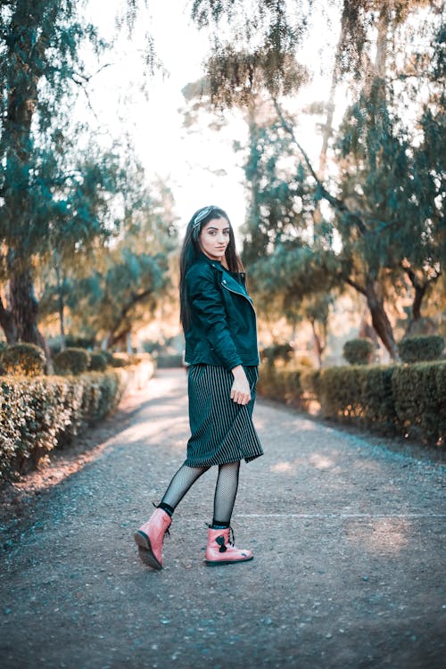 Woman in Black Jacket, Skirt, and Pink Boots