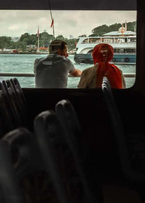 A man and woman sitting on a bus looking out at the water