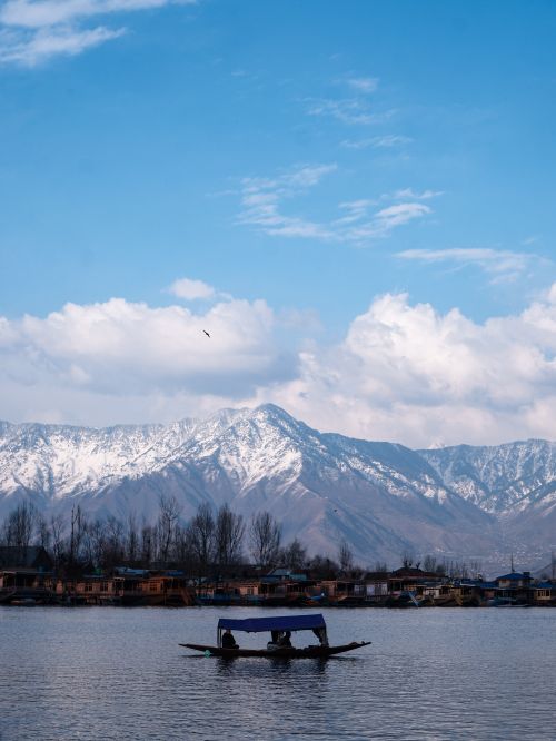 Free A serene boat ride on a lake with snow-capped mountains in the background, showcasing nature's beauty. Stock Photo
