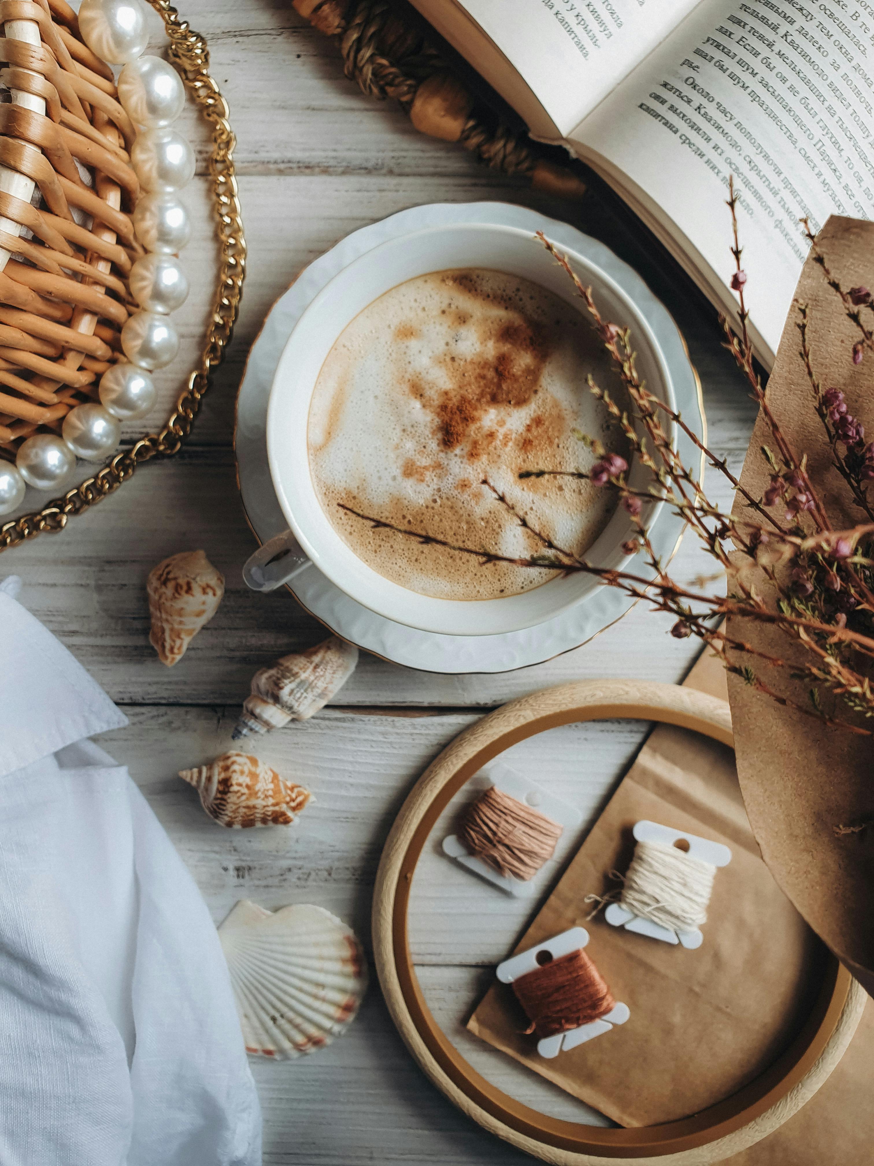 Captivating top view of a cappuccino amidst an artistic flat lay featuring seashells and thread.
