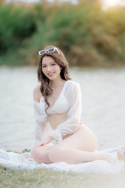 A beautiful asian woman in white clothes sitting on the grass
