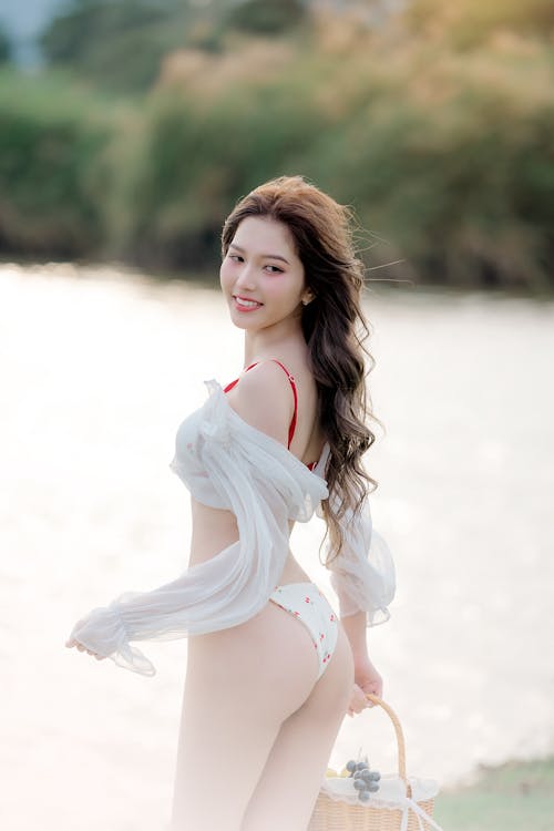 A beautiful asian woman in white underwear posing by the water