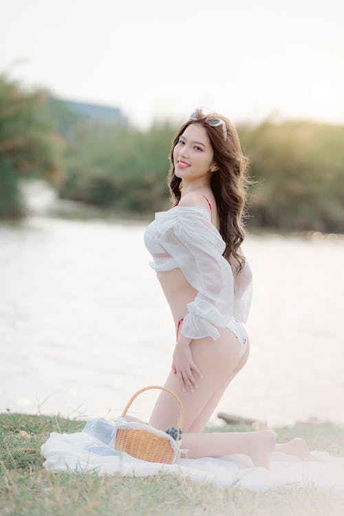 A beautiful woman in white underwear posing near the water