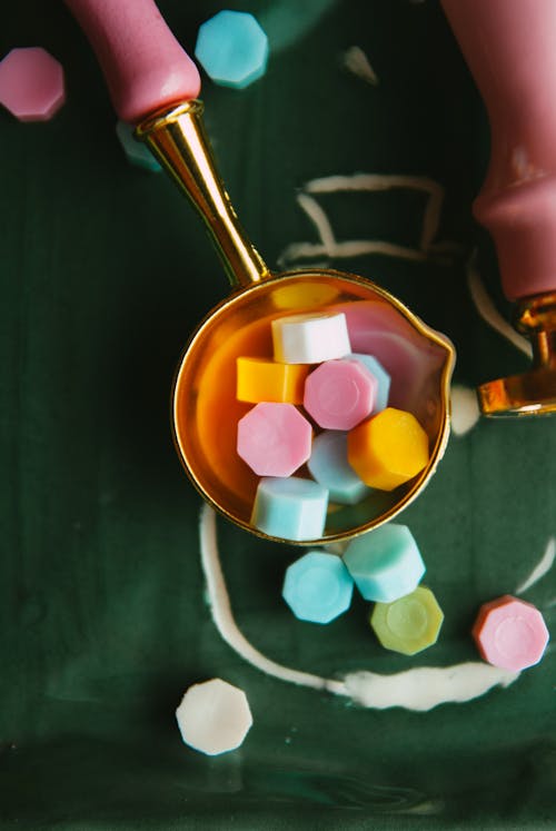 A spoon with colorful candy in it and a measuring cup