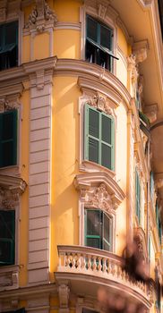Ornate yellow building facade with green shutters in urban setting, featuring balconies.