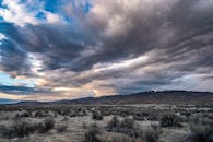 在壮观的云层下，崎岖山脉的广阔视野描绘了宁静而原始的荒野