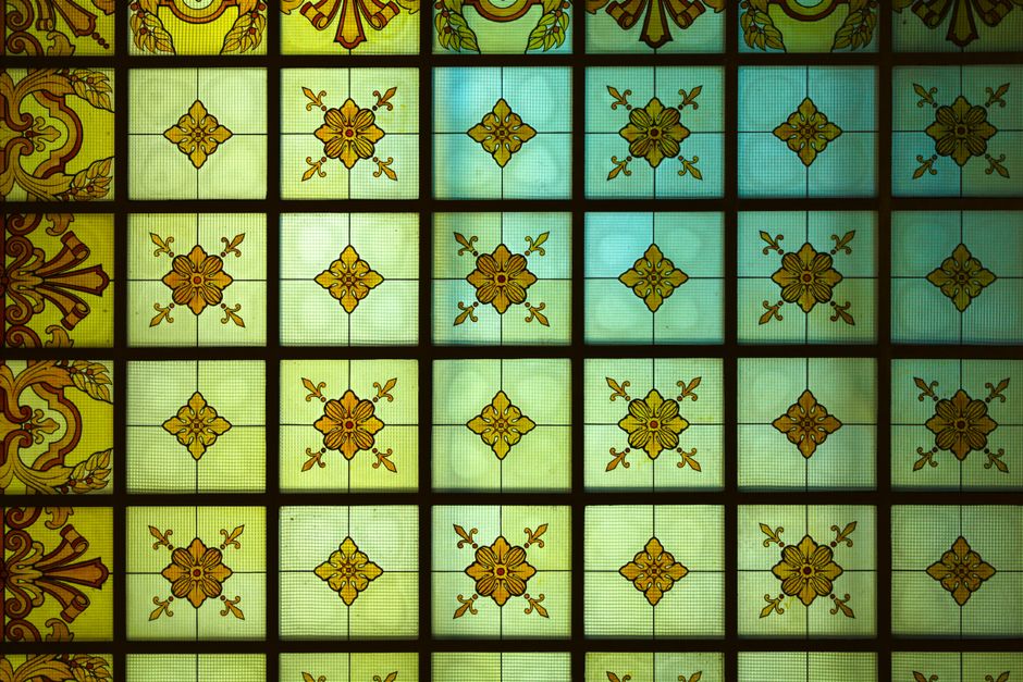 Detailed view of ornate stained glass with geometric floral patterns in warm hues.