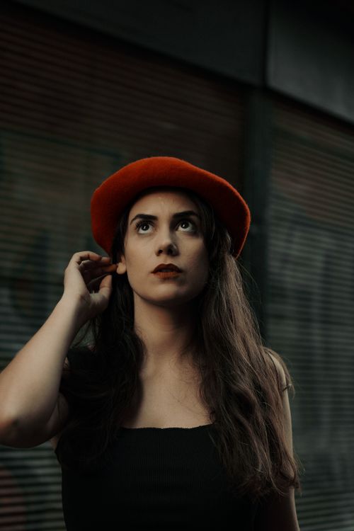 Free Portrait of a fashionable woman in a red hat, captured with dramatic lighting for a striking effect. Stock Photo