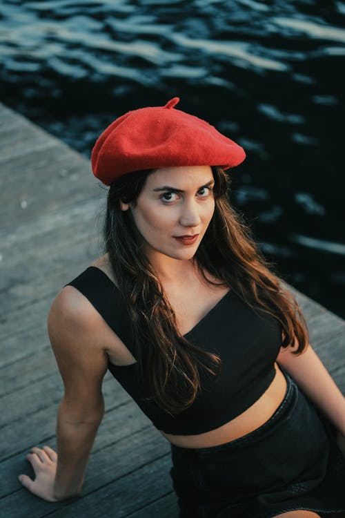 Free A woman in a red beret sitting on a dock Stock Photo