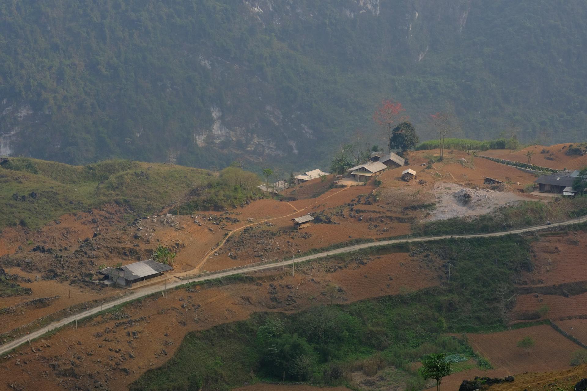 Scenic aerial view of rural farmhouses on a foggy hillside landscape.