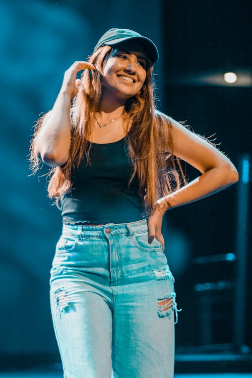 A woman in jeans and a hat on stage