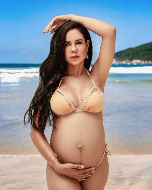 A pregnant woman in a bikini on the beach