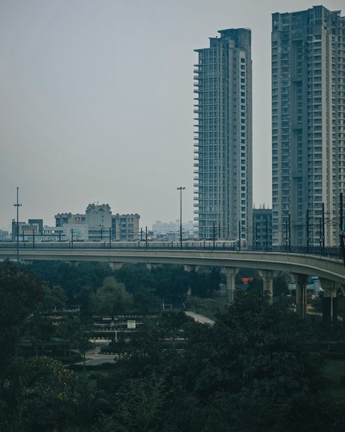 Free A dramatic view of urban skyscrapers towering above a highway overpass, set in a cityscape. Stock Photo