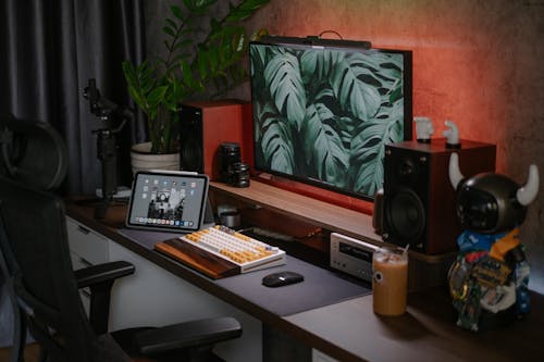 A desk with a computer, monitor, and speakers