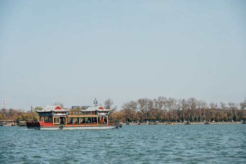 Free A serene view of a traditional Chinese boat sailing on a lake at the Summer Palace in Beijing, China. Stock Photo