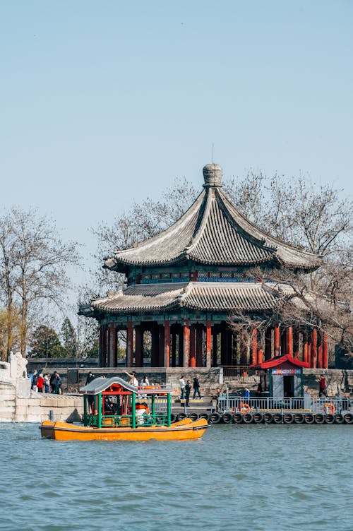 A boat is floating in the water near a pagoda