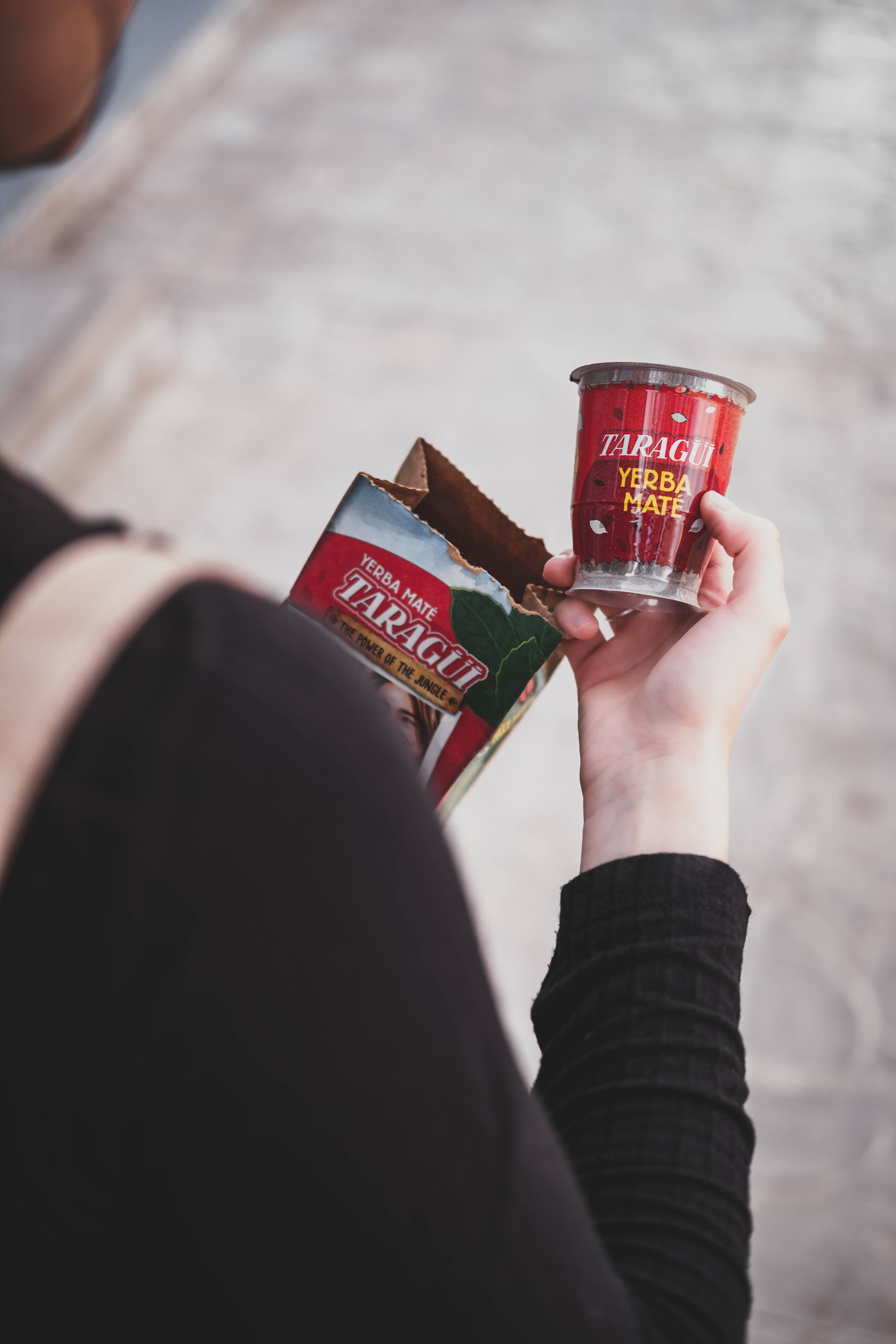 Person holding a cup of yerba mate and packaging, showcasing beverage design.